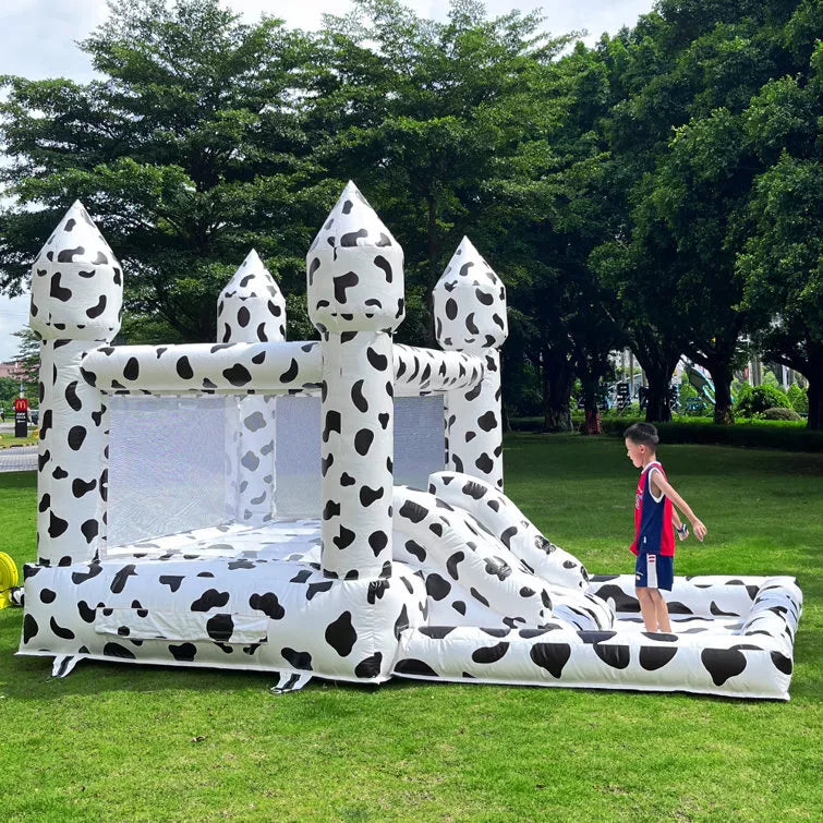 Casa de rebote inflable con temática de vaca con tobogán y piscina de pelotas