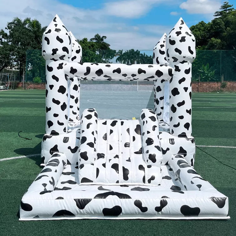 Casa de rebote inflable con temática de vaca con tobogán y piscina de pelotas