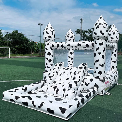 Casa de rebote inflable con temática de vaca con tobogán y piscina de pelotas