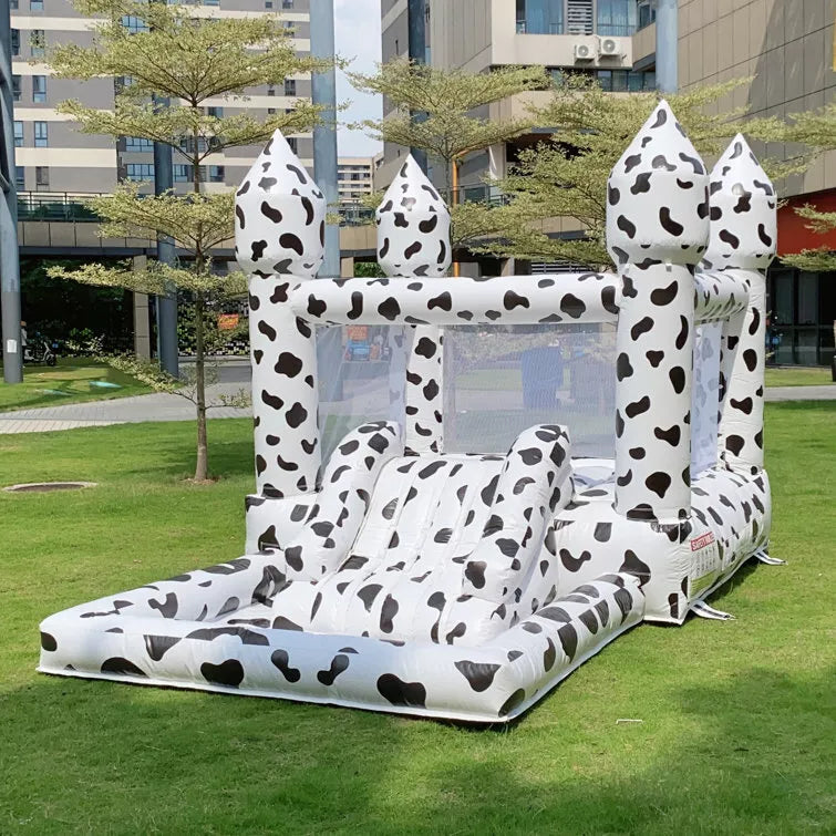 Casa de rebote inflable con temática de vaca con tobogán y piscina de pelotas